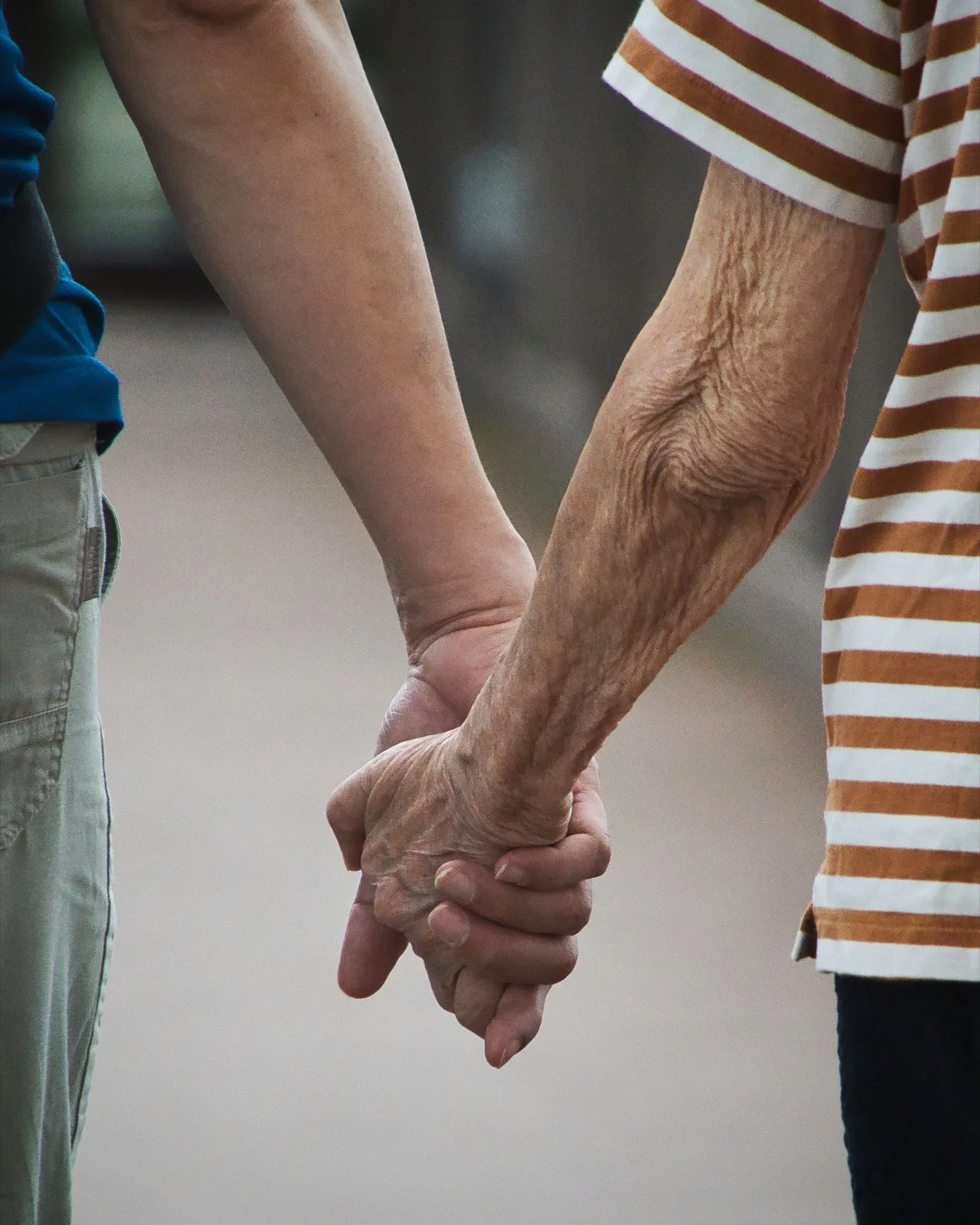 A young hand holding an elderly hand